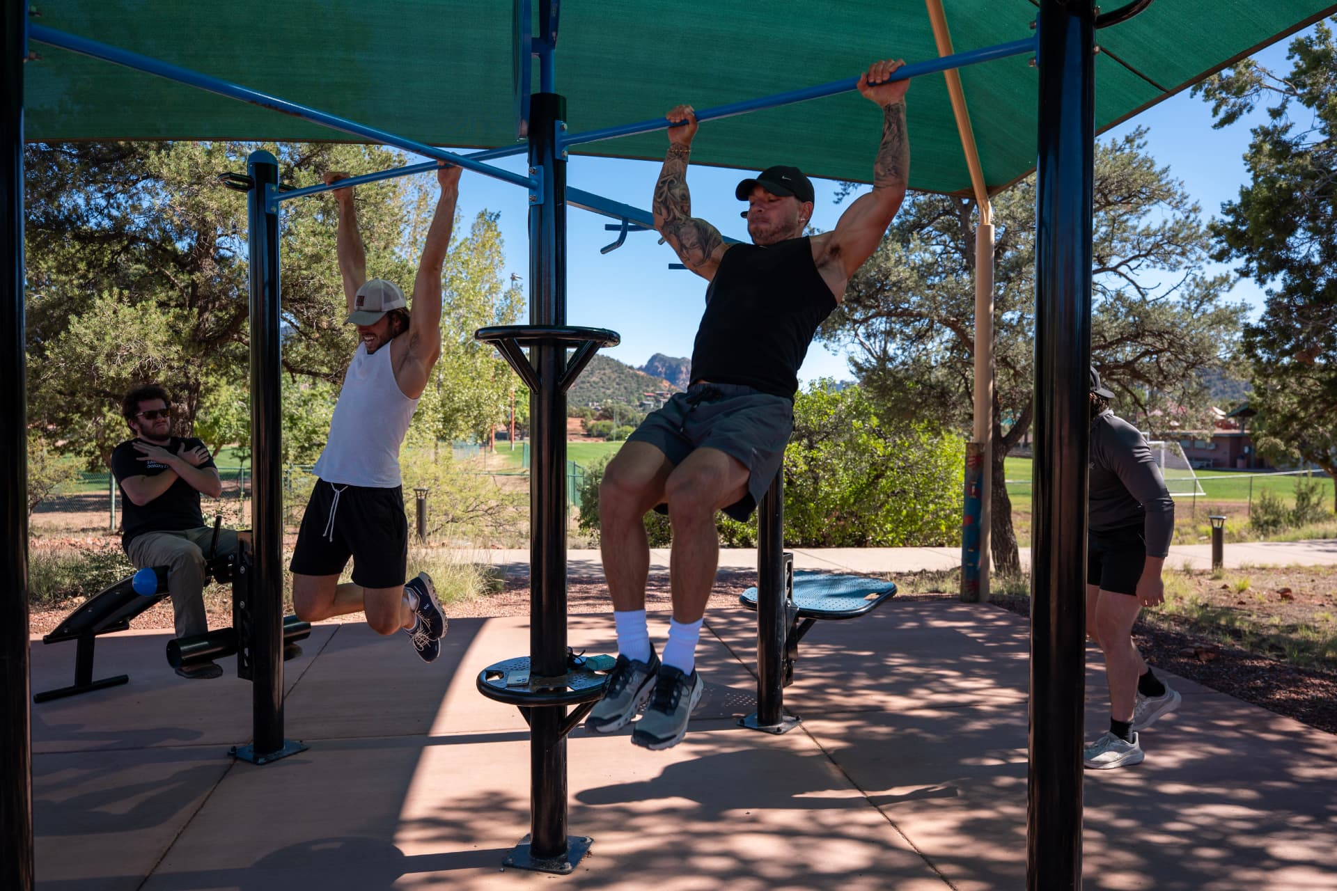 Men doing pull-ups together at an outdoor exercise area